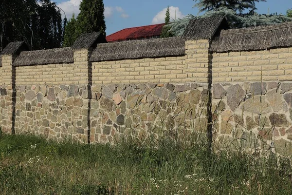 通りの緑の芝生に石やレンガで作られた柵の灰色の茶色の壁 — ストック写真