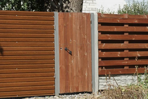 bir kapalı kırmızı ahşap kapı ve kırsal bir sokakta kahverengi çitin bir parçası