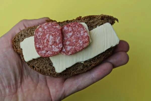 Mão Segura Sanduíche Com Pedaço Pão Marrom Salsicha Salame Manteiga — Fotografia de Stock