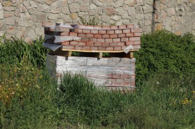 Kahverengi asfalt levhalar bir paletin üzerinde, sokaktaki yeşil çimlerin üzerinde duruyor.