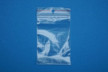 Küçük şeffaf, boş bir plastik poşet mavi bir masanın üzerinde duruyor.
