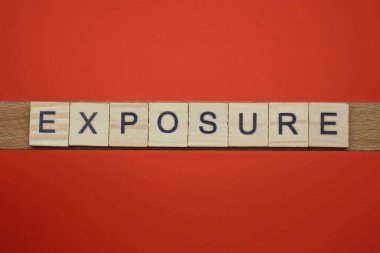 kırmızı bir masa üzerinde siyah yazı tipi olan gri ahşap harflerden maruz kalma sözcüğünü metin