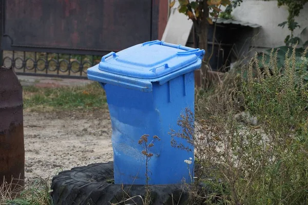 Bir Kapalı Mavi Plastik Çöp Kutusu Dışarıda Yeşil Bitki Örtüsü — Stok fotoğraf