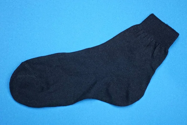 One Black Fabric Sock Lies Blue Table — Stock Fotó