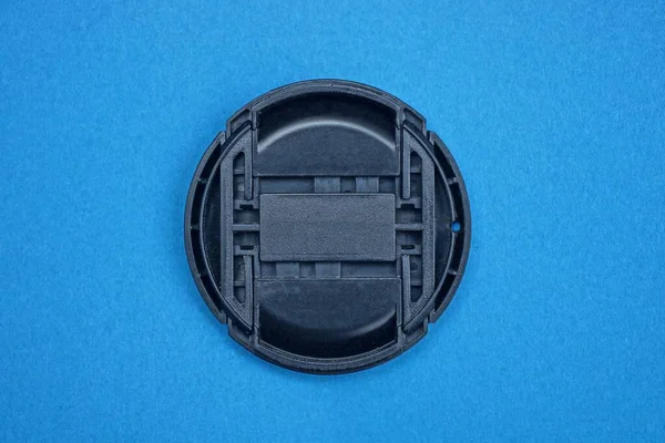 Jedna Czarna Plastikowa Nasadka Obiektywu Leży Niebieskim Stole — Zdjęcie stockowe