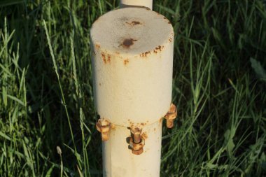 Dışarıdaki yeşil çimlerde pas lekeli elektrik kabloları için bir kutu ile gri demir çubuk.