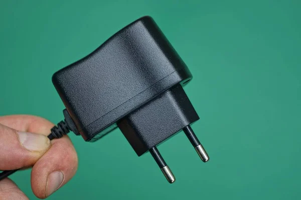 Los Dedos Sostienen Adaptador Cargador Negro Sobre Fondo Verde —  Fotos de Stock