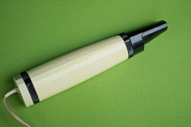 Eski bir plastik beyaz siyah elektrikli saç kurutma makinesi yeşil bir masada yatıyor.