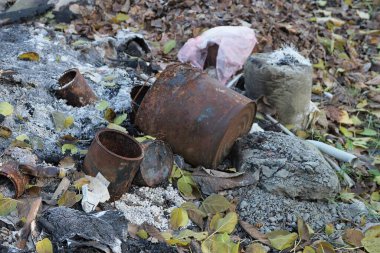 Kahverengi paslı teneke kutular doğadaki gri çöp yığınında yatıyor.
