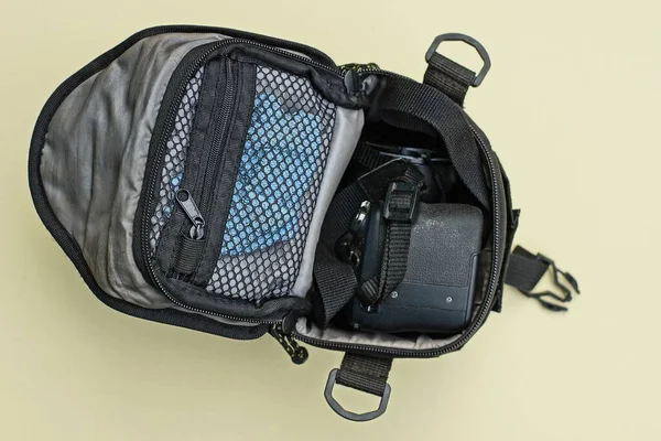 Siyah kameralı gri bir çanta kahverengi bir masada duruyor.