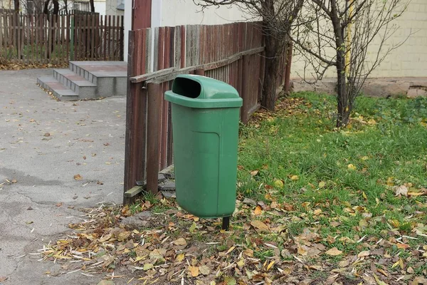 Ein Grüner Plastikmülleimer Steht Gras Vor Einem Braunen Holzzaun — Stockfoto