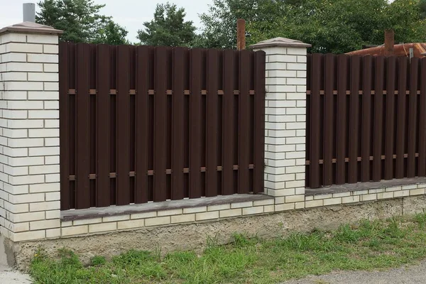 Çitin bir kısmı kahverengi metalden ve beyaz tuğlalardan yapılmıştı.