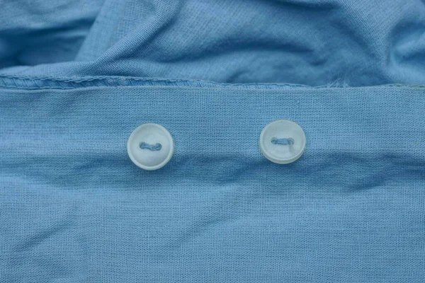 Дві Маленькі Пластикові Білі Кнопки Шматочку Синьої Сорочки Тканини — стокове фото