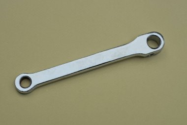 Gri metal pedaldan yapılmış bir bisikletin parçası kahverengi bir masanın üzerinde duruyor.