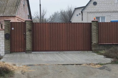 Büyük kahverengi kapalı metal kapı ve duvarın bir kısmı gri tuğlalardan ve demirden yapılmış gri kaldırımda.