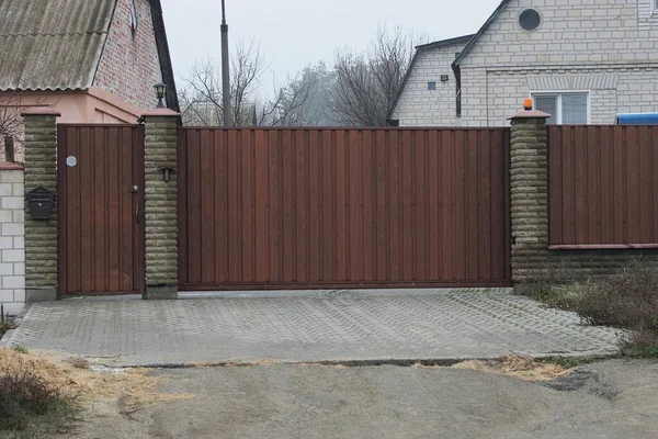 Büyük kahverengi kapalı metal kapı ve duvarın bir kısmı gri tuğlalardan ve demirden yapılmış gri kaldırımda.