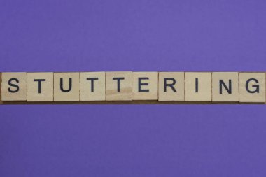 Gri kelime küçük kare ahşap harflerle kekeliyordu. Eflatun arka planda siyah yazı tipi vardı.