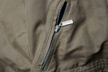 Cebinde gri metalik fermuar ve yeşil ceket kumaşı.