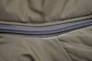 Uzun kahverengi bir plastiğin yeşil bir giysi örtüsünün fermuarı.