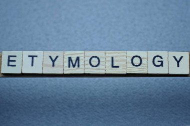 kahverengi ahşap harflerden etimoloji sözcüğünü yaz gri bir masanın üzerinde siyah yazı tipi olan.