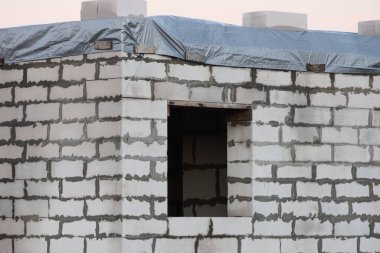 Tamamlanmamış beyaz tuğlalardan oluşan bir ev duvarı ve boş bir pencere.