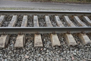 Gri demir rayları ve molozların arasında beton yatakları olan demiryolu