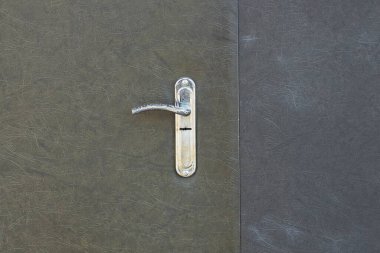 Bir beyaz metal kapı tokmağı ve caddede gri demir bir kapı.