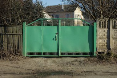 Eski yeşil kapalı demir kapı ve kırsal sokaktaki gri çit 