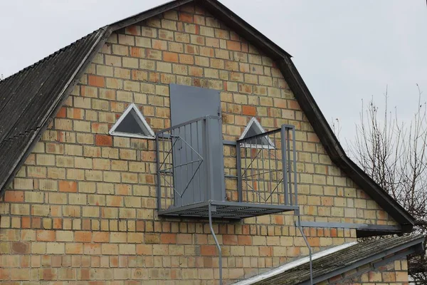 一座灰色的开着的金属阳台 位于一座带门窗的私人住宅阁楼的棕色砖墙上 — 图库照片