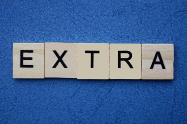 mavi arkaplanda siyah yazı tipi olan küçük kare tahta harflerle ekstra gri kelime