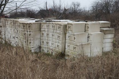 Büyük beyaz bir bina yığını sokaktaki kuru ot ve bitki örtüsünün köpük bloklarını tuğlalar haline getiriyor.