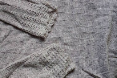 Eski bir elbisenin üzerindeki iki kirli gri yün kollu kumaş.