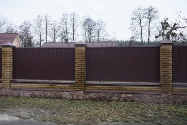 Özel demir tuğlaların bir parçası. Caddedeki yeşil çimlerin duvarlarında kahverengi çitler var.