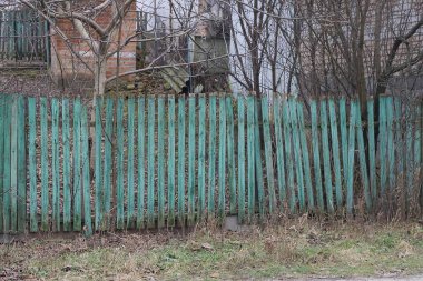 yeşil ahşap eski duvar çitleri caddede çimlerin altında ağaç dallarının altında 