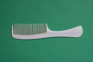 Eski gri plastik bir tarak yeşil bir masada yatıyor.