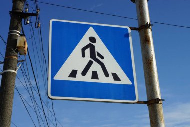 Mavi gökyüzü arka planında metal bir sütunun üzerinde yaya geçidi.