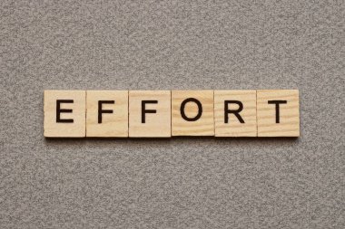 Gri bir masa üzerinde siyah yazı tipi olan kahverengi ahşap harflerden kelime çabası metin