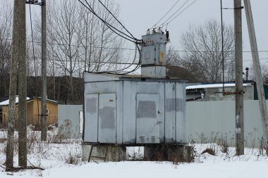 one large gray metal transformer stands on a winter street in white snow