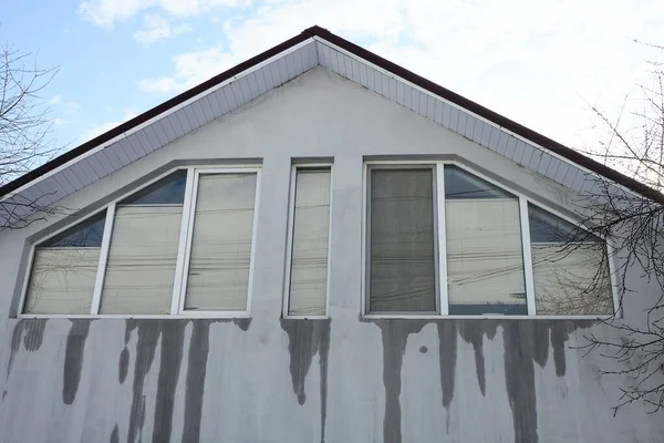 big windows on a gray wet concrete wall in the attic of a private house