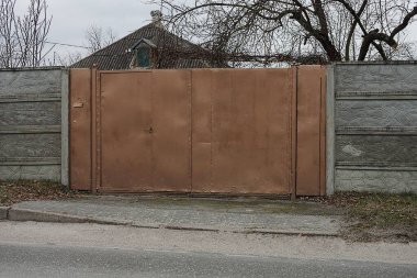 Büyük kahverengi metal bir kapı ve dışarıda gri beton bir duvar var.