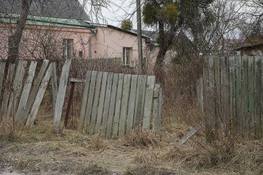 Eski kırık bir çitin parçası kuru otlardaki gri ahşap tahtalardan yapılmış.