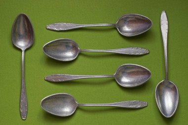 dishes made of many old aluminum spoons lie on a green table