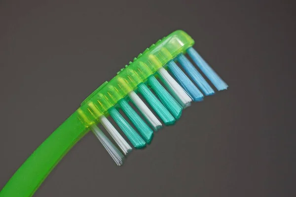 Část Jednoho Zubního Kartáčku Barevnými Štětinami Zelené Plastové Rukojeti Šedém — Stock fotografie