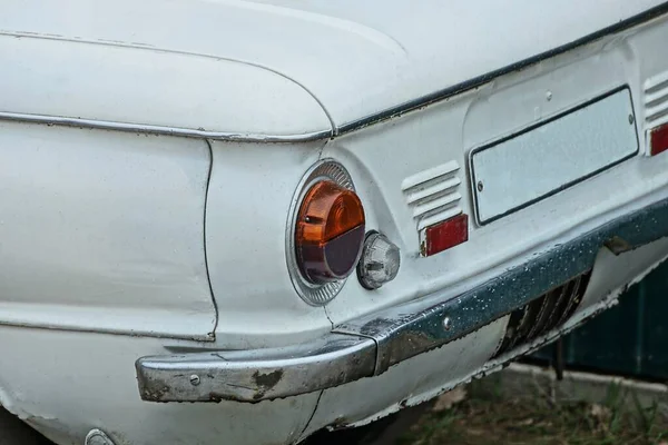 灰色の鉄のリアバンパーの近くの白いレトロな車の上の1ラウンド古い赤いヘッドライト — ストック写真