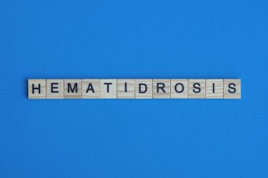 mavi arkaplanda siyah yazı tipi olan küçük kare tahta harflerle hematidroz.