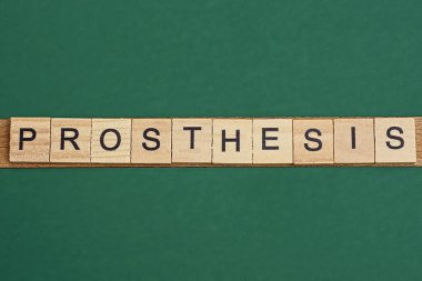 Yeşil masadaki küçük tahta harflerden gelen gri kelime protezi.