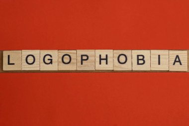 Kırmızı bir masanın üzerinde siyah yazı tipi olan gri ahşap harflerden logofobi kelimesine mesaj at.