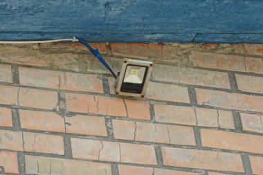 Sokağın ortasında kahverengi bir duvarda asılı duran bir lamba.