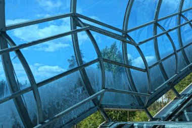 Tünelin içindeki mavi plastik duvarda gri metal parmaklıklar var.