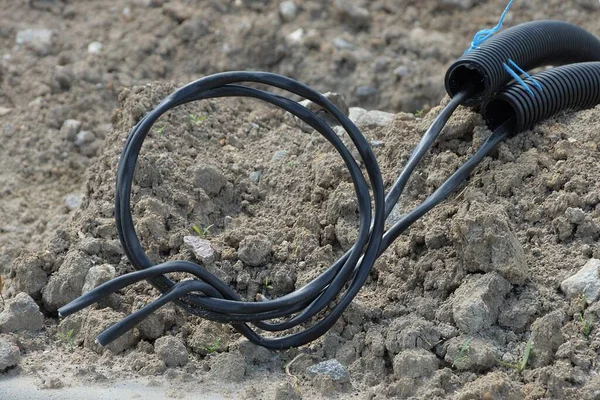 Een Zwarte Elektrische Kabel Een Plastic Slang Ligt Grijze Grond — Stockfoto